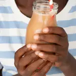 enfant qui tient une bouteille de jus de bouye